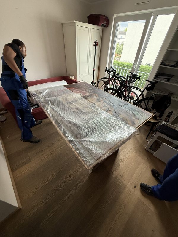 Großes gerahmtes Bild liegt in Luftpolsterfolie eingeschlagen auf einem Tisch