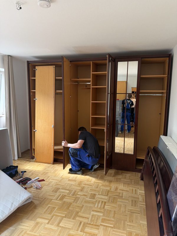 Mitarbeiter richtet die Türen eines mehrtürigen Kleiderschranks in einem Schlafzimmer aus