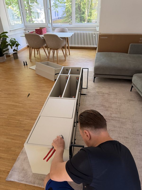 Blick von oben auf einen Mitarbeiter, der an einem liegenden Sideboard mit Schubladenauszügen arbeitet