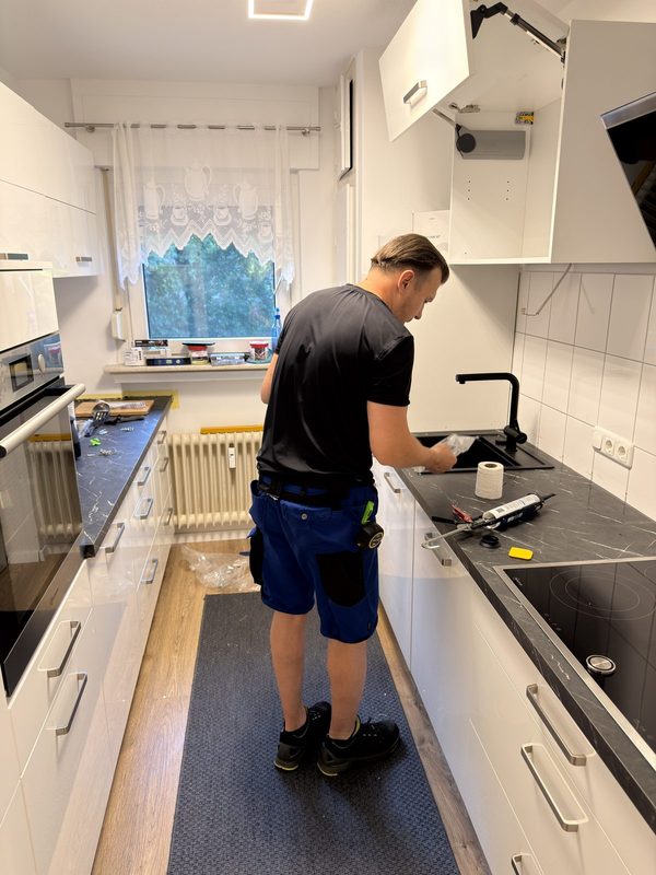 Mitarbeiter setzt eine schwarze Spüle in den Ausschnitt einer Arbeitsplatte ein